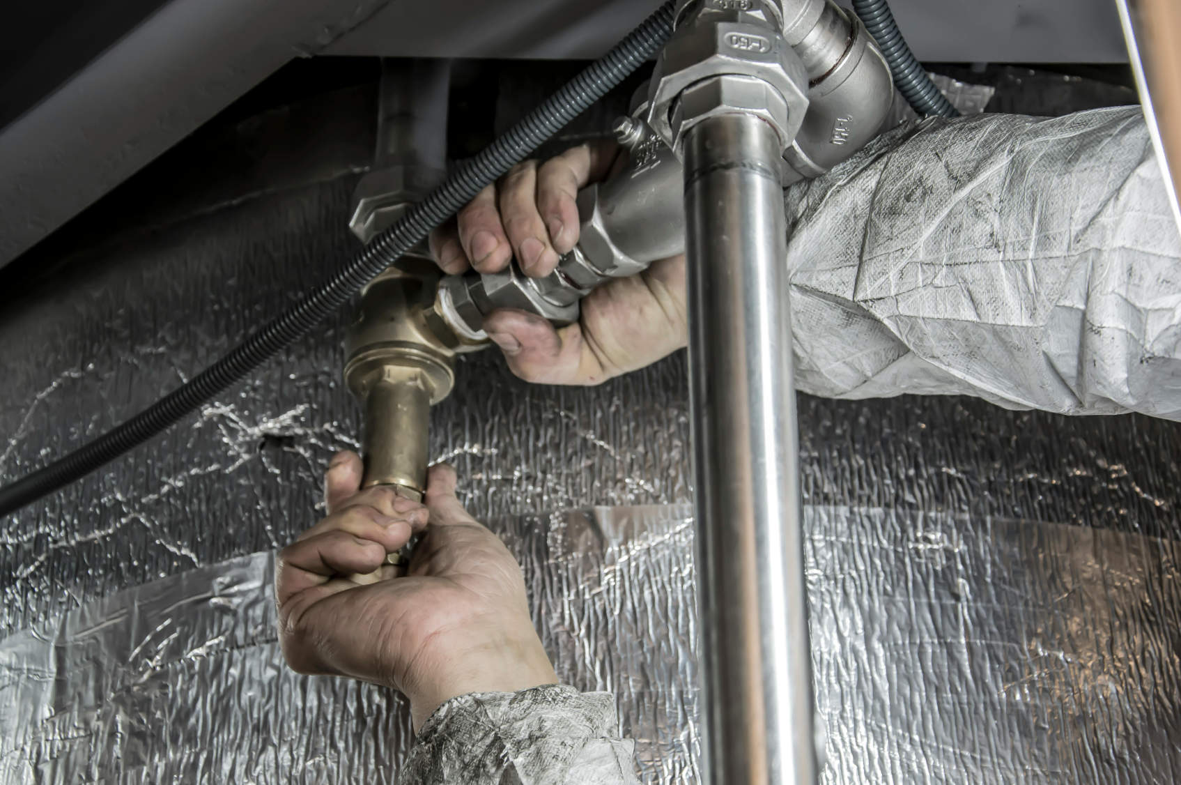 Plumber in Chicago, Illinois fixing pipes under a sink, representing the importance of reliable local web hosting for plumbing businesses